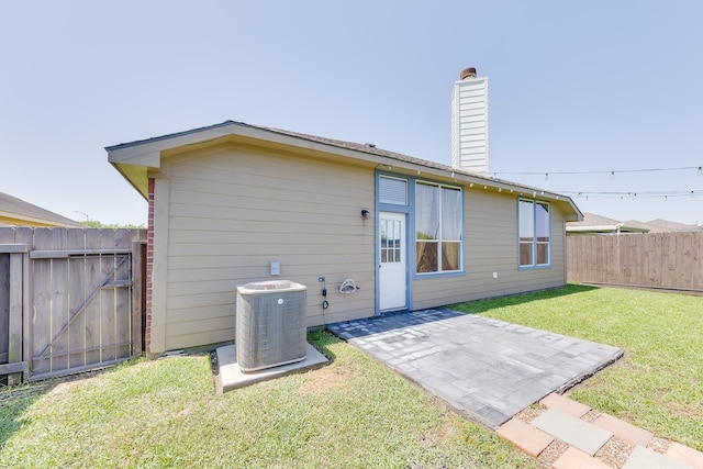 rear view of property with a lawn, a chimney, fence, cooling unit, and a patio