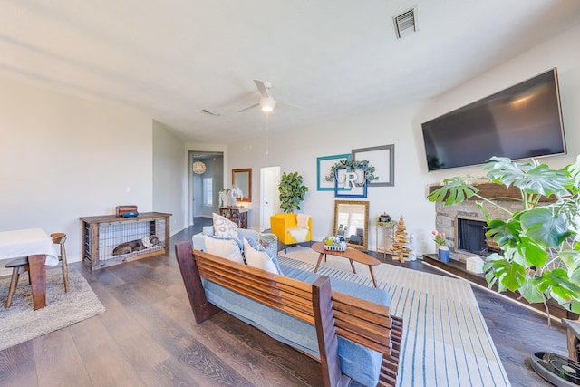 living room with ceiling fan, a fireplace, visible vents, wood finished floors, and baseboards