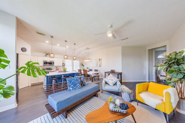 living room featuring visible vents, ceiling fan, vaulted ceiling, and wood finished floors