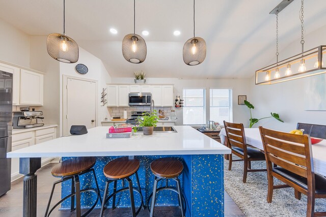 kitchen with backsplash, white cabinets, a breakfast bar, and stainless steel appliances
