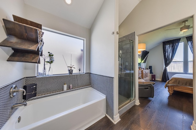 ensuite bathroom with connected bathroom, a garden tub, wood finished floors, and lofted ceiling