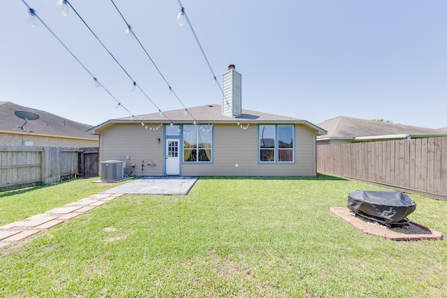 rear view of house featuring central AC unit, a lawn, a chimney, a fenced backyard, and a patio
