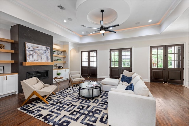 living room with a raised ceiling, visible vents, ornamental molding, and a large fireplace
