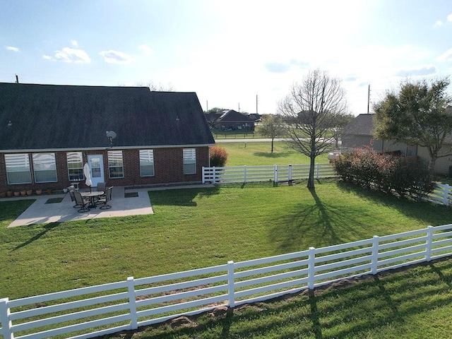 exterior space with a lawn, a patio, brick siding, and a fenced backyard