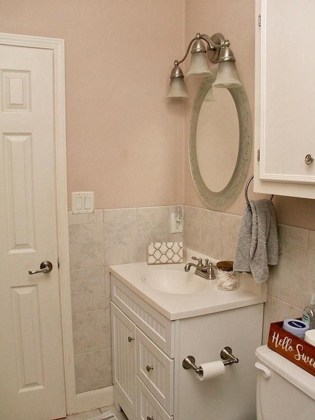 bathroom with wainscoting, tile walls, vanity, and toilet