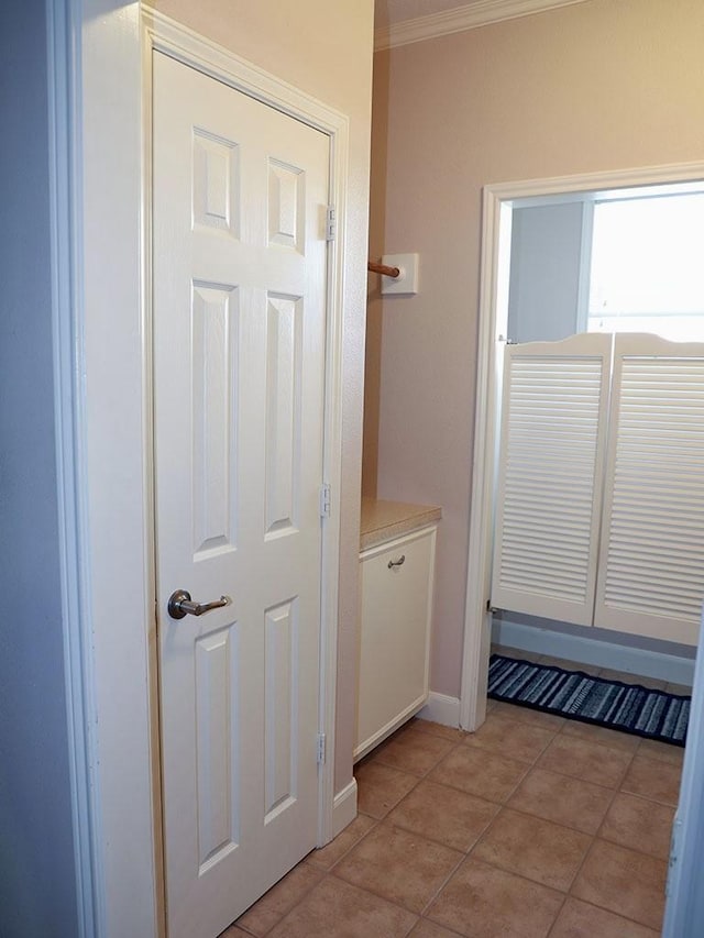 interior space featuring crown molding, baseboards, and light tile patterned floors