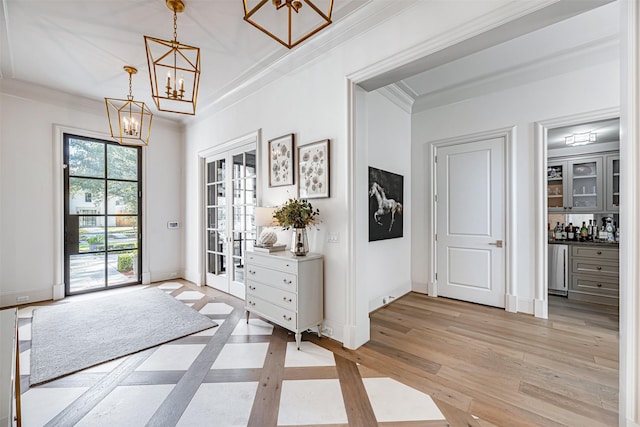 3028 Locke Ln, Houston, TX 77019 - entryway with a chandelier, a dry bar, light wood-style flooring, ornamental molding, and baseboards