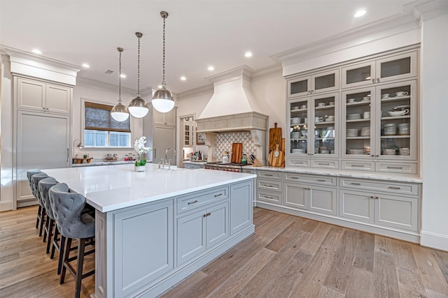 3028 Locke Ln, Houston, TX 77019 - kitchen featuring custom exhaust hood, backsplash, ornamental molding, a kitchen breakfast bar, and light countertops