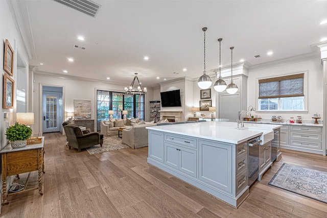 3028 Locke Ln, Houston, TX 77019 - kitchen with crown molding, light countertops, a center island with sink, open floor plan, and light wood-style flooring