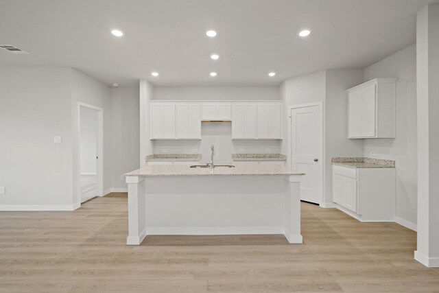 17824 Lionheart Rd, Conroe, TX 77306 - kitchen featuring visible vents, a kitchen island with sink, white cabinetry, a sink, and light wood finished floors