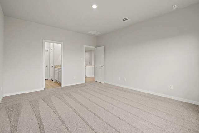 17824 Lionheart Rd, Conroe, TX 77306 - unfurnished bedroom with light colored carpet, recessed lighting, baseboards, ensuite bathroom, and visible vents