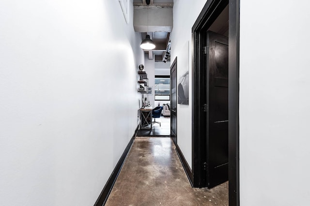 hall with a high ceiling, finished concrete flooring, and baseboards