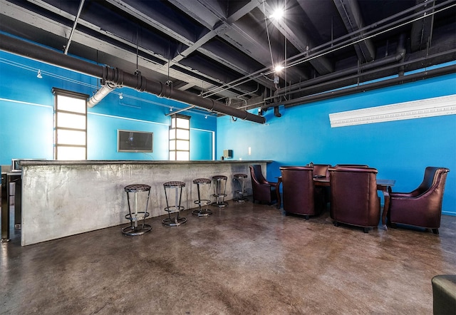 bar featuring a dry bar, concrete floors, and a healthy amount of sunlight