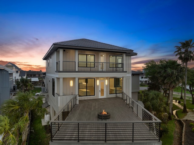 1303 Oahu Dr, Tiki Island, TX 77554 - back of property at dusk with a balcony, an outdoor fire pit, and board and batten siding