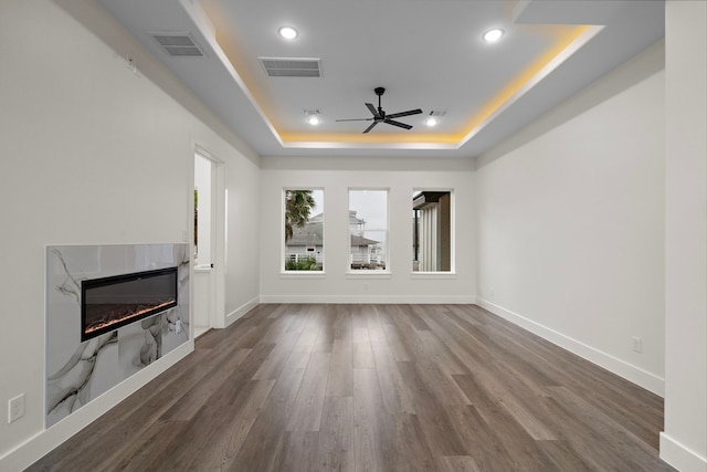 1303 Oahu Dr, Tiki Island, TX 77554 - unfurnished living room with a raised ceiling, a ceiling fan, a premium fireplace, wood finished floors, and recessed lighting