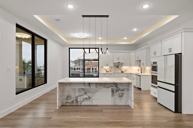 1303 Oahu Dr, Tiki Island, TX 77554 - kitchen with stainless steel appliances, a raised ceiling, a sink, a center island, and white cabinetry