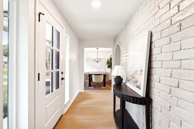 5606 Arbor Vitae Dr, Houston, TX 77092 - corridor featuring light wood-type flooring, brick wall, a chandelier, and healthy amount of natural light