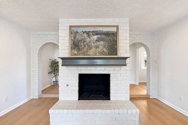 5606 Arbor Vitae Dr, Houston, TX 77092 - detailed view of wood finished floors, a textured ceiling, arched walkways, and a brick fireplace