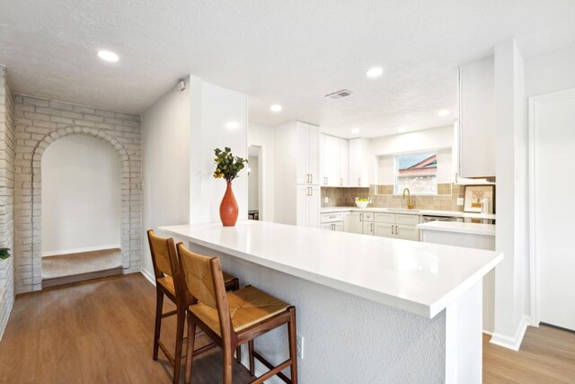 5606 Arbor Vitae Dr, Houston, TX 77092 - kitchen with light wood finished floors, a kitchen breakfast bar, white cabinetry, light countertops, and backsplash