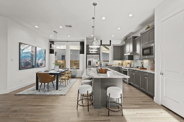 500 Dove Meadow Ln, Katy, TX 77493 - kitchen featuring stainless steel appliances, gray cabinetry, wood finish floors, light stone countertops, and recessed lighting