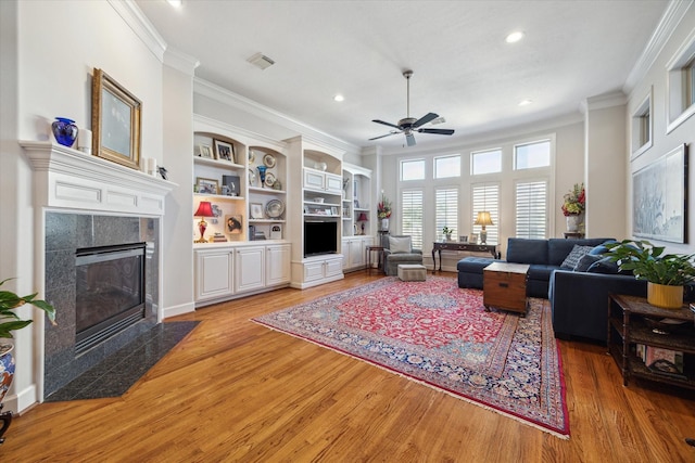 5768 Sugar Hill Dr, Houston, TX 77057 - living room featuring a tiled fireplace, ornamental molding, ceiling fan, light wood finished floors, and recessed lighting