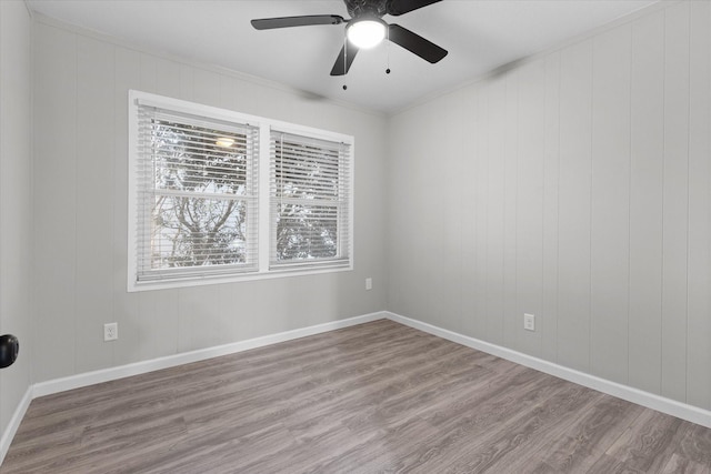 empty room featuring ceiling fan, baseboards, crown molding, and wood finished floors