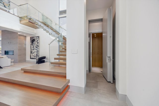 310 E Cowan Dr, Houston, TX 77007 - staircase featuring a fireplace, a high ceiling, and baseboards