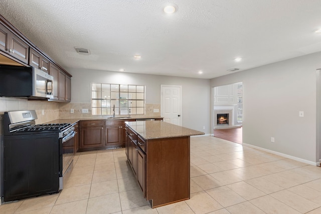 10223 Dude Rd, Houston, TX 77064 - kitchen with tasteful backsplash, light tile patterned floors, a center island, appliances with stainless steel finishes, and light stone counters