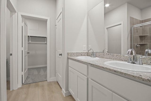 17836 Lionheart Rd, Conroe, TX 77306 - full bathroom featuring double vanity, wood finished floors, a spacious closet, and an enclosed shower