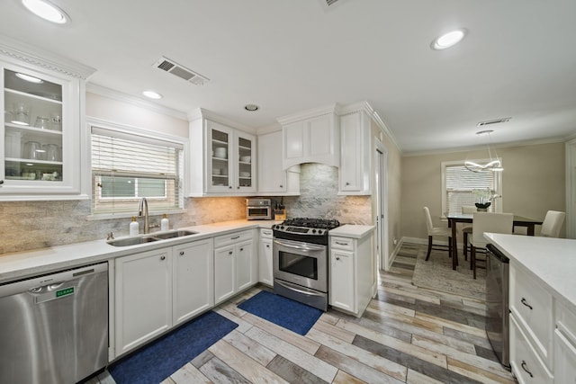 kitchen with light countertops, stainless steel appliances, ornamental molding, and a sink