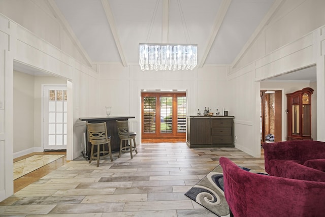 living area featuring wood finished floors, a decorative wall, high vaulted ceiling, and beamed ceiling