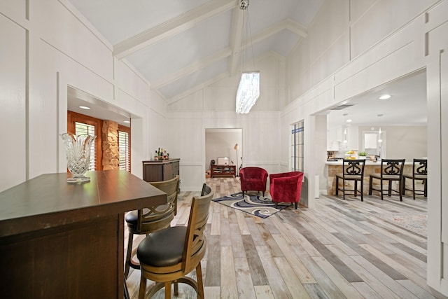interior space featuring beam ceiling, a decorative wall, high vaulted ceiling, wood finished floors, and pendant lighting