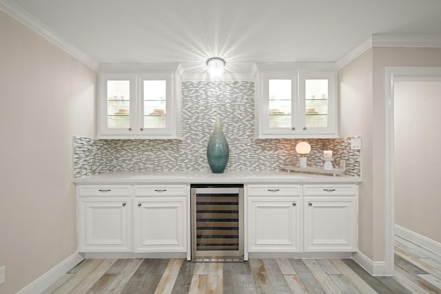 bar with light wood-type flooring, ornamental molding, wine cooler, and tasteful backsplash