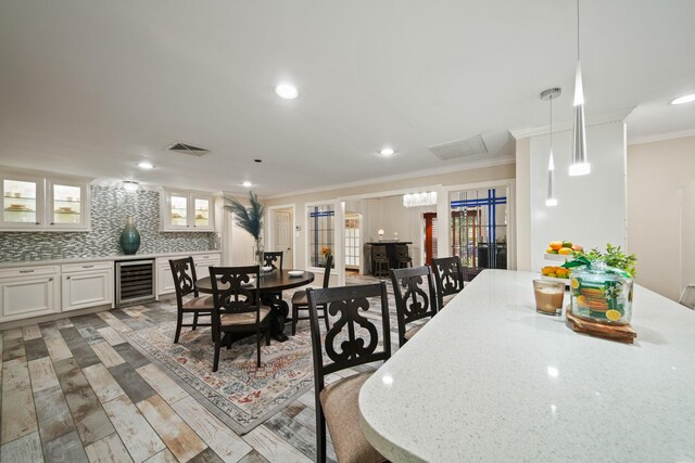 dining room featuring visible vents, crown molding, wood finished floors, beverage cooler, and recessed lighting