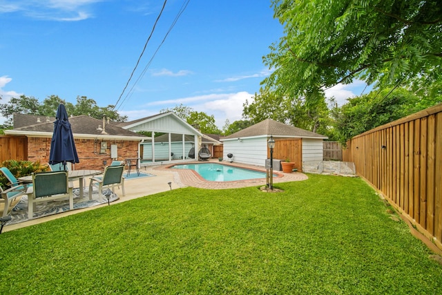 view of swimming pool with a patio, a fenced backyard, a fenced in pool, a lawn, and an outbuilding