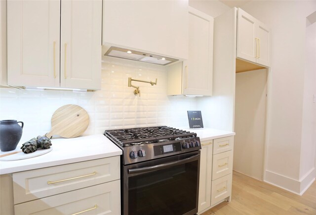 603 Neyland St, Houston, TX 77022 - kitchen featuring stainless steel gas range oven, backsplash, light countertops, light wood-style floors, and white cabinets
