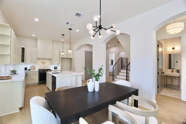 603 Neyland St, Houston, TX 77022 - dining area featuring arched walkways, light wood finished floors, recessed lighting, and stairway
