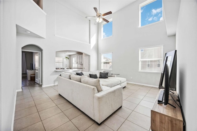 5914 Prince Place Dr, Rosenberg, TX 77471 - living room featuring light tile patterned floors, baseboards, arched walkways, ceiling fan, and a towering ceiling