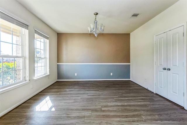 unfurnished dining area with visible vents, baseboards, a chandelier, and wood finished floors