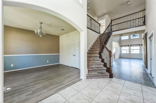foyer entrance with a chandelier, stairs, a towering ceiling, and wood finished floors