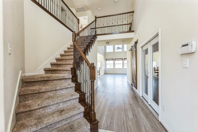 stairs featuring visible vents, a high ceiling, baseboards, and wood finished floors