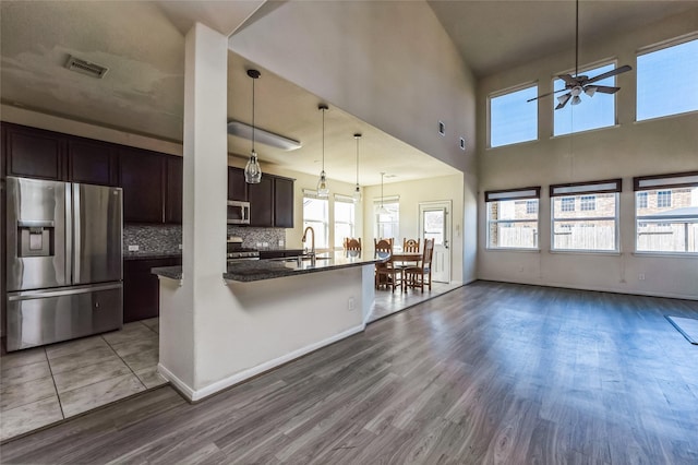 kitchen with dark brown cabinetry, visible vents, appliances with stainless steel finishes, wood finished floors, and open floor plan