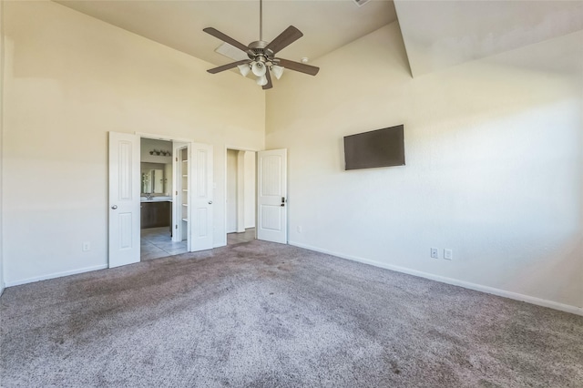 unfurnished bedroom with high vaulted ceiling, ensuite bath, baseboards, and carpet floors