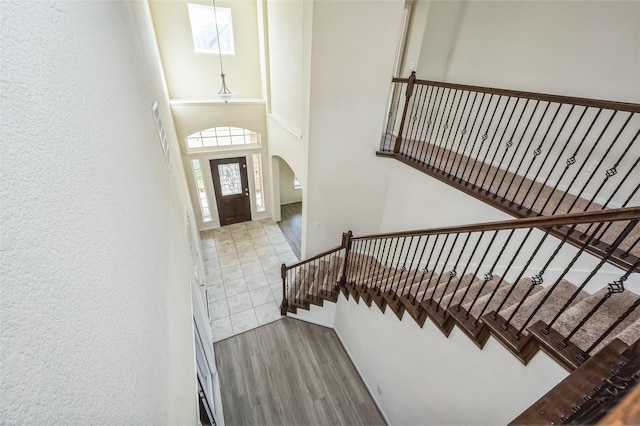 entrance foyer featuring arched walkways, stairs, a towering ceiling, and wood finished floors