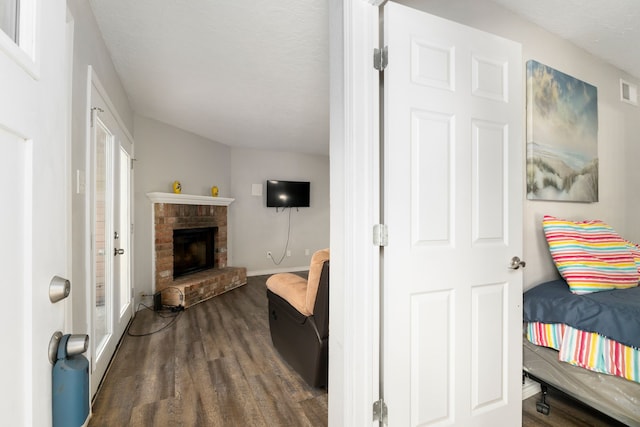 bedroom featuring baseboards, a brick fireplace, dark wood-type flooring, and visible vents