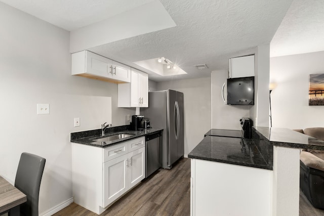 kitchen featuring a textured ceiling, a sink, dishwasher, range, and dark wood-style floors