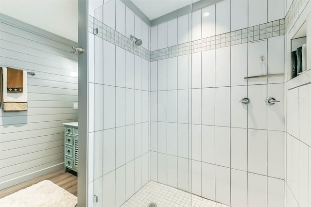 full bathroom with a tile shower and wood finished floors