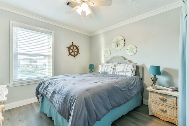 bedroom featuring crown molding, a ceiling fan, visible vents, wood finished floors, and baseboards