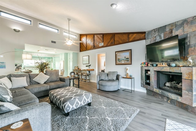 living room featuring visible vents, ceiling fan, high vaulted ceiling, a tile fireplace, and wood finished floors