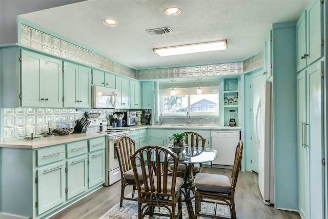 kitchen with light wood-style floors, white appliances, tasteful backsplash, visible vents, and a sink